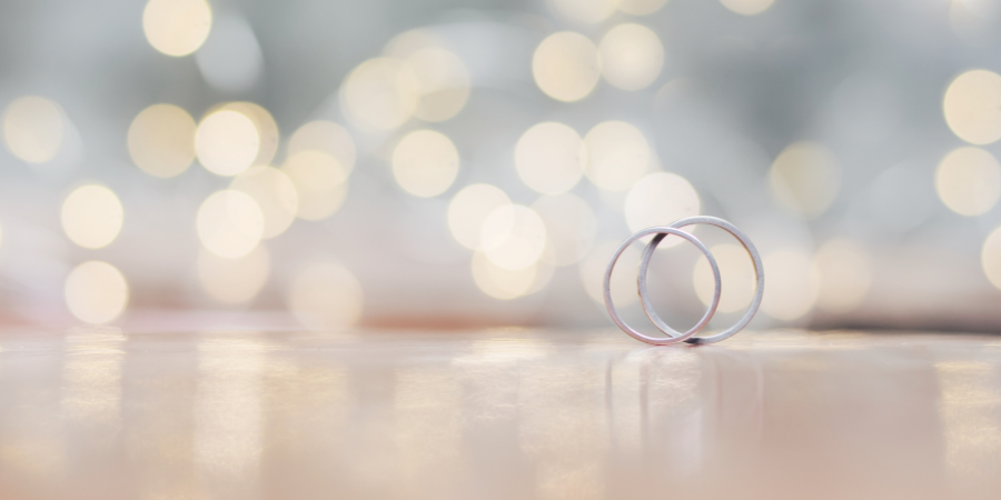 Unscharf fotografierte Eheringe vor leuchtenden Lichtern – Symbol für Liebe, Verbundenheit und die Atmosphäre einer Hochzeitsfeier.